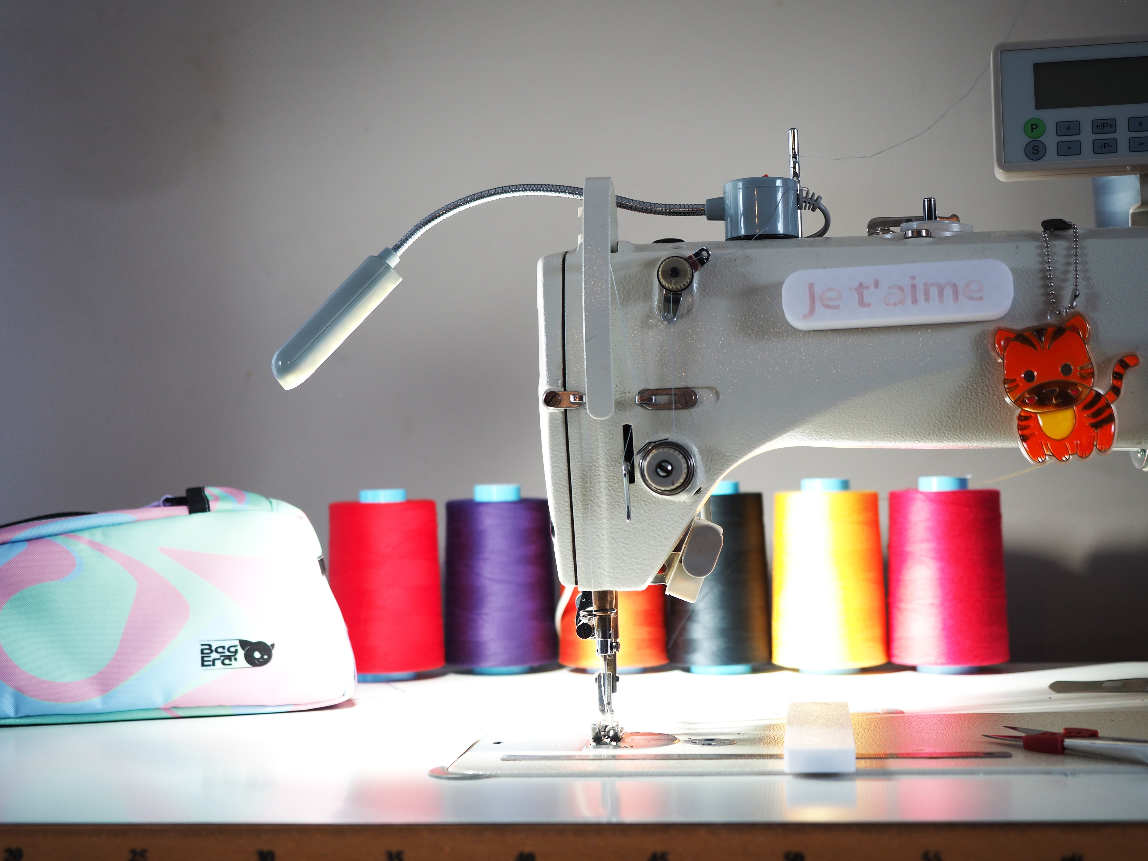 Photo de l'atelier pointant la machine à coudre avec une sacoche et des fils de coutures de tout les couleurs en fond